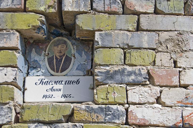 A Kyrgyz brick-built tomb with photo-nameplate in a lonely graveyard.