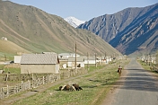 A horseman rides along the deserted street of a small village.