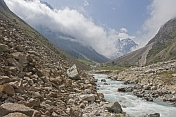 A stream rushes down the boulder-strewn river valley of the Ala-Archa Canyon.