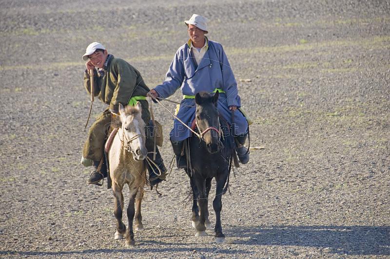 Two Mongolian horsemen crossing a gravel desert plain near the Khyargas Nuur lake, near Naranbulag.