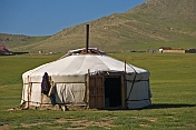 A Mongolian yurt with open door, in a field.