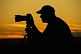 Western cameraman is silhouetted against the yellow sunset.