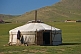 A Mongolian yurt with open door, in a field.