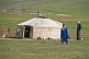 Image of Mongolian man and boy stand next to their yurt.
