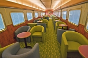 Tables and armchairs in the Red Gum Lounge Car of the Ghan long distance train.