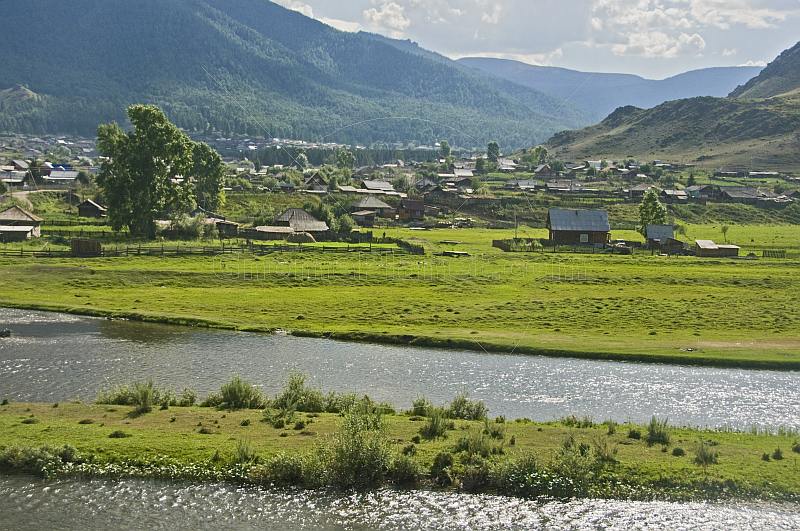 Small Russian town of log houses nestles between the Altai Mountains and the river.