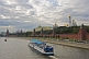Image of A sight-seeing boat on the Moscow River passes the red walls of the Kremlin, under a cloudy sky.