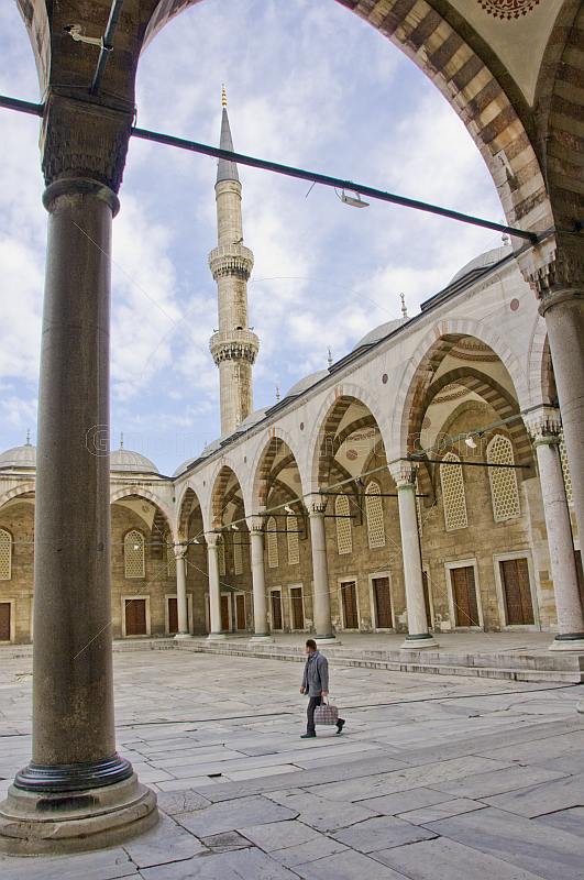 Man walks across courtyard of Sultan Ahmet\\'s blue mosque in Sultanahmet.