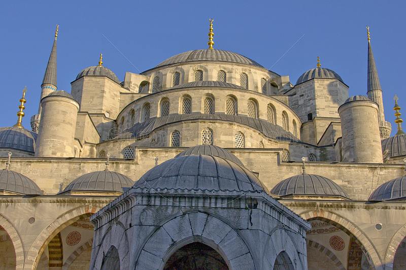 Domes of the Ahmet Camii Blue Mosque lit by evening sunshine.