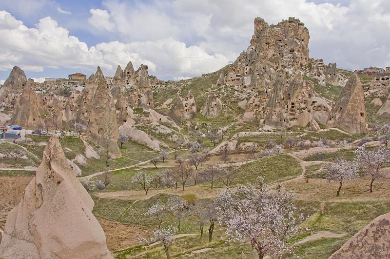The dramatic rock castle dominates the blossomed valley of tuft dwellings.