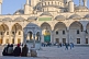 Image of Worshippers wait in the courtyard of the Ahmet Camii Blue Mosque lit by evening sunshine.