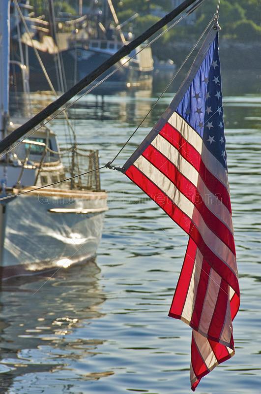 U.S.A. flag 'Stars and Stripes' hangs from boom on sailing ship in harbour.