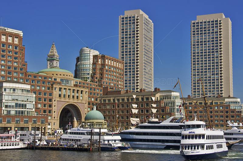 Ships and boats of many types fill the inner harbor, backed by tall office buildings.