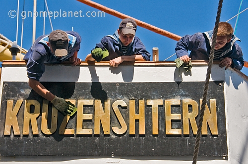 Young Russian cadets clean the brass nameplate of the sailing ship 'Kruzenshtern'.