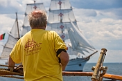 Mariner on the quarterdeck of the 3 masted barque 'Picton Castle' watches the tallship 'Sagres' pass by.