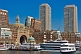 Image of Ships and boats of many types fill the inner harbor, backed by tall office buildings.