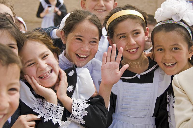 Smiling school Children in traditional black and white uniforms greet visitors from abroad.