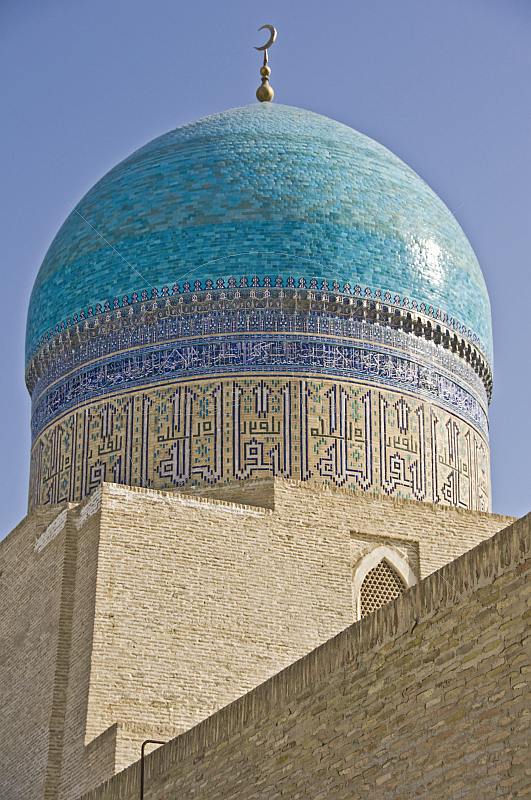 Sunshine reflects off the luminous blue tilework on a dome of the Miri-Arab Madrassah.
