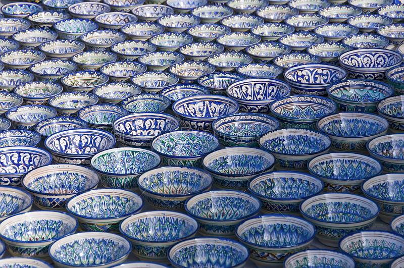 Trader\\'s display of blue and white pottery bowls tempts the traveller in Bukhara\\'s Central Asian Bazaar.