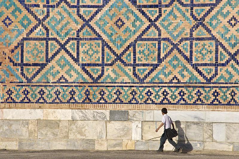 Small boy walks in front of the tiled mosiacs on the Sher-Dor Madrasah.