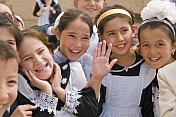 Smiling school Children in traditional black and white uniforms greet visitors from abroad.