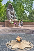 Two girls walk past the Crying Mother war memorial with eternal flame which honours the 400,000 Uzbek soldiers who died in WWII.
