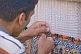 Image of Uzbek carpet weaver knots another thread to his silk rug.