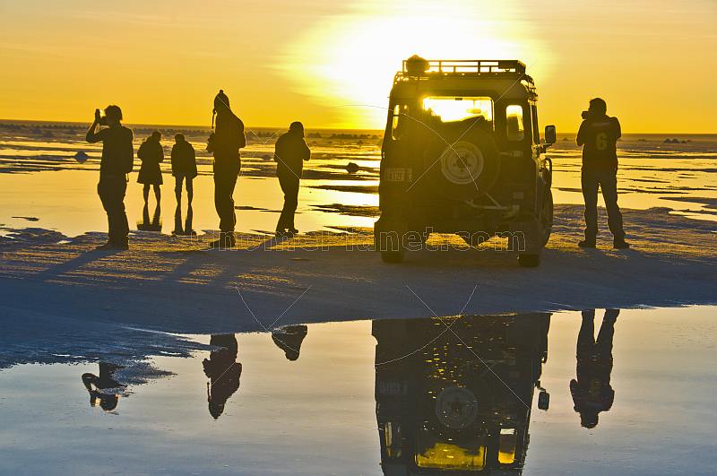 Tourists with Land Rover viewing the sunset on the Uyuni Salt Flats.