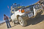 Man loads luggage on a Toyota 4WD Land Cruiser prior to crossing salt flats.