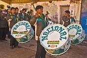 Bass drummers in a brass band marching through the streets in a traditional town festival.