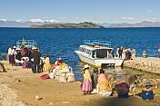 Traditionally dressed locals unload a boat on the Isla del Sol in Lake Titicaca.