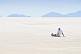 Image of Man sits on the Uyuni Salt Flats to admire the view.