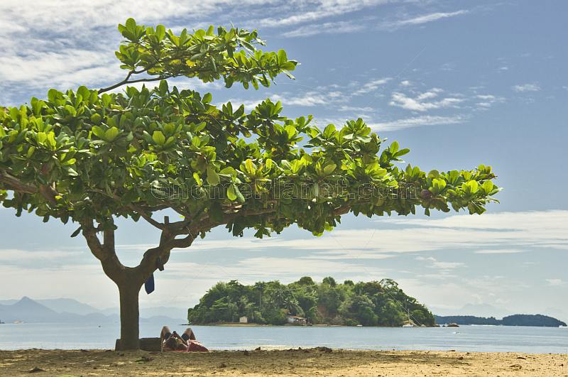 Woman uses mobile phone on beach in the Bahia Da Ilha Grande.