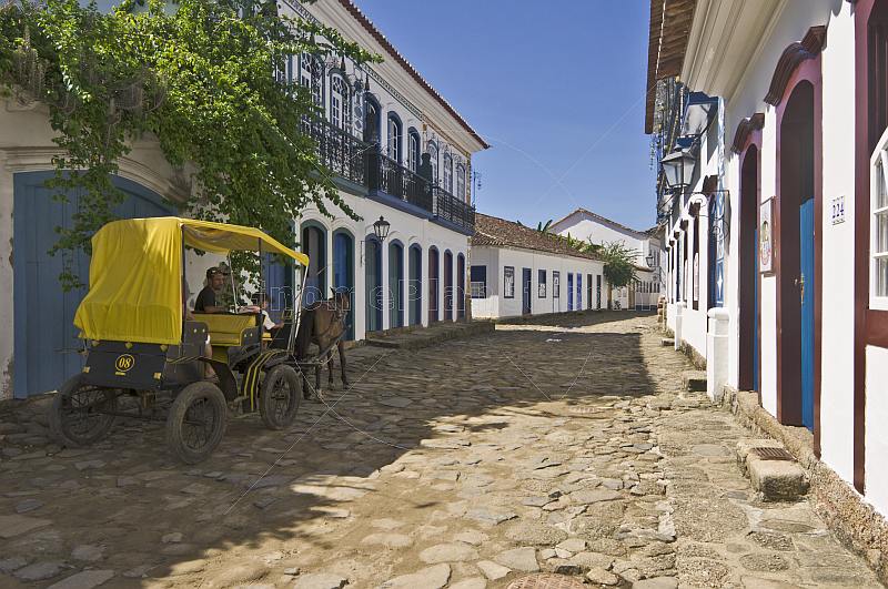 Horse carriage drives along cobbled street in colonial old town.