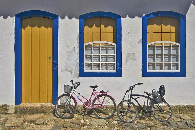 Bicycles in front of colorful colonial house door and windows.