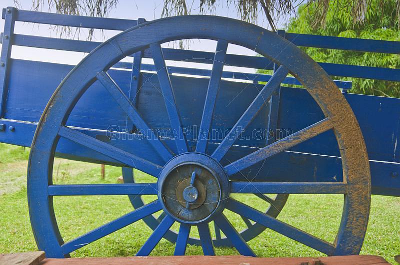 Blue wooden farm cart with mud on the wheel.
