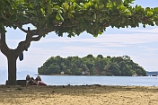 Woman uses mobile phone on beach in the Bahia Da Ilha Grande.