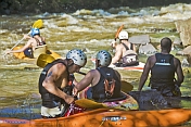 A group of canoeists watch others negotiate rough water.