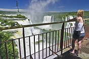 A female traveller views the waterfalls cascading into the Iguazu River.