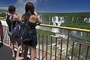 Travellers view the waterfalls cascading into the Iguazu River.