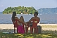 Couple sit on beach looking at island in the Bahia Da Ilha Grande.