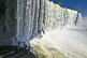 Image of Travellers view the waterfalls cascading into the Iguazu River.