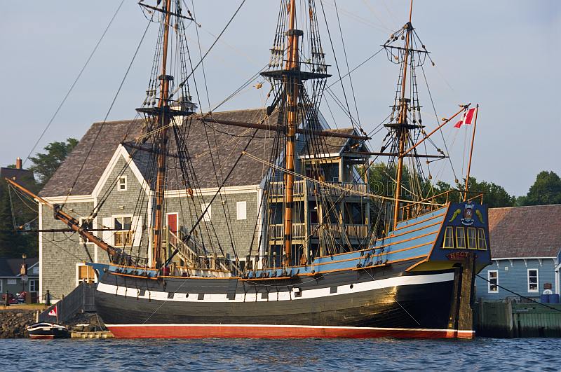 Replica pirate ship 'Hector' moored to the Pictou wharf, alongside colonial style buildings.