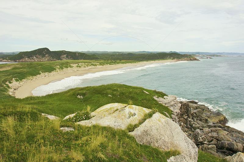 View over the grassy headland to beaches and forested hills at Sandbanks Provincial Park.