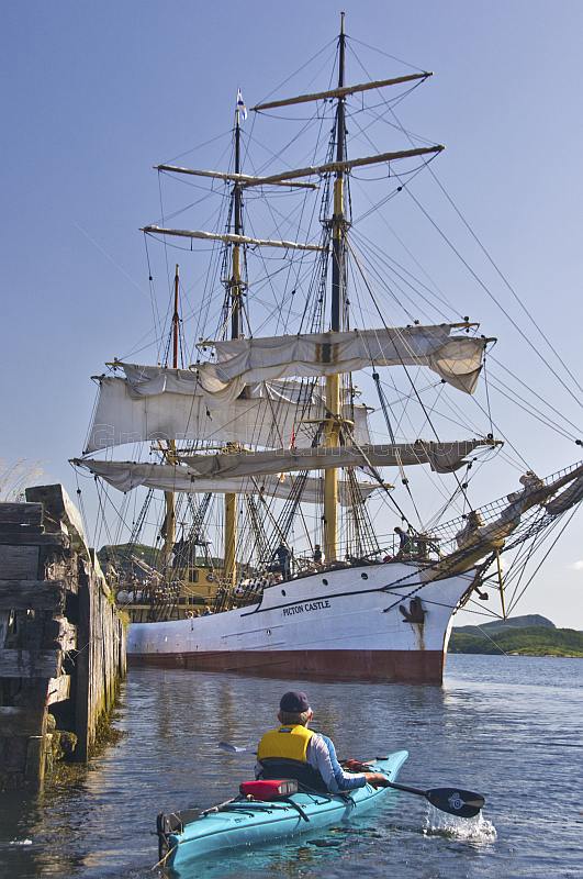 A canoeist watches the tallship 'Picton Castle' prepare to set sail and  leave port.