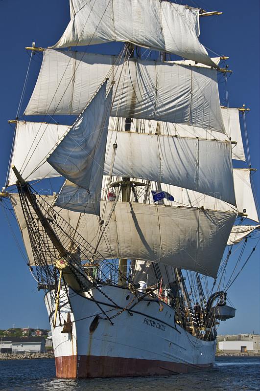 The tallship 'Picton Castle' leaves harbor on a sunny morning under full sail.