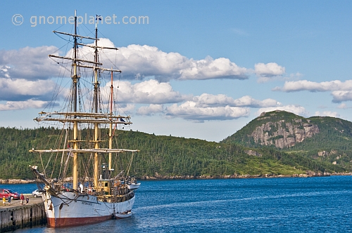 The barque 'Picton Castle' moored at the old fishing wharf amidst forests and mountains.