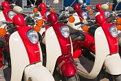 Red and white Honda motor scooters waiting for hire.