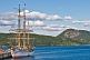 Image of The barque 'Picton Castle' moored at the old fishing wharf amidst forests and mountains.