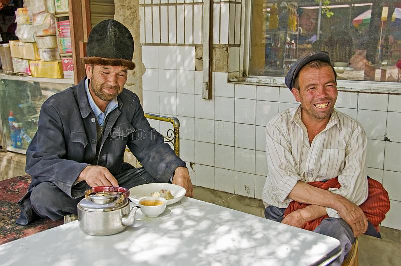 Local Kashgar men pass the time at a local teashop, eating meat pasties and drinking green tea from bowls.